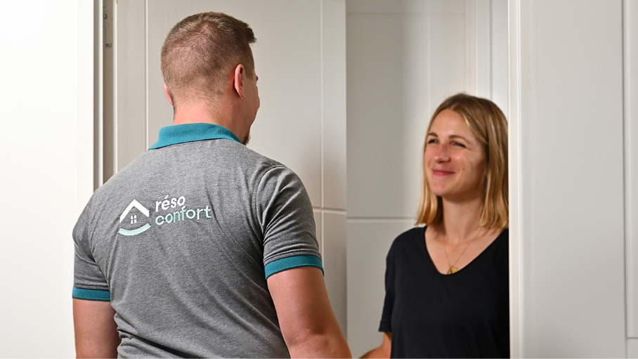 Un technicien souriant est accueilli par une cliente.