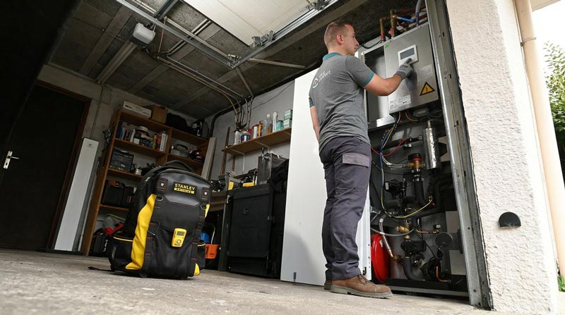 Technicien ajustant une chaudière dans un garage